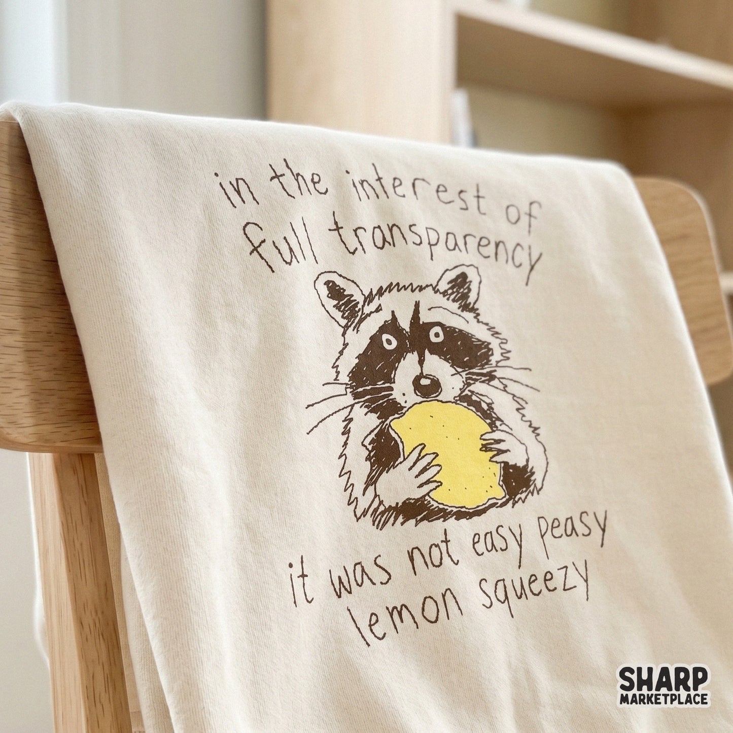 Trendy indie-style raccoon illustration with a yellow lemon and witty text, ideal for DIY apparel, tumblers, and relatable office wall art designs.