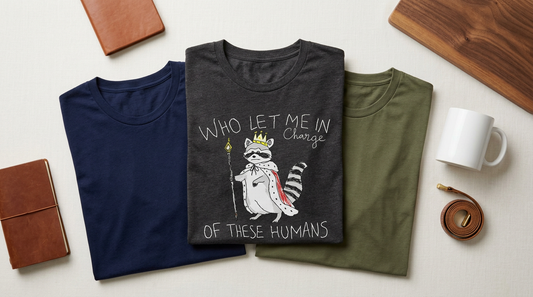 Flat lay of folded men's t-shirts and a ceramic mug on a neutral background for Father's Day POD planning.