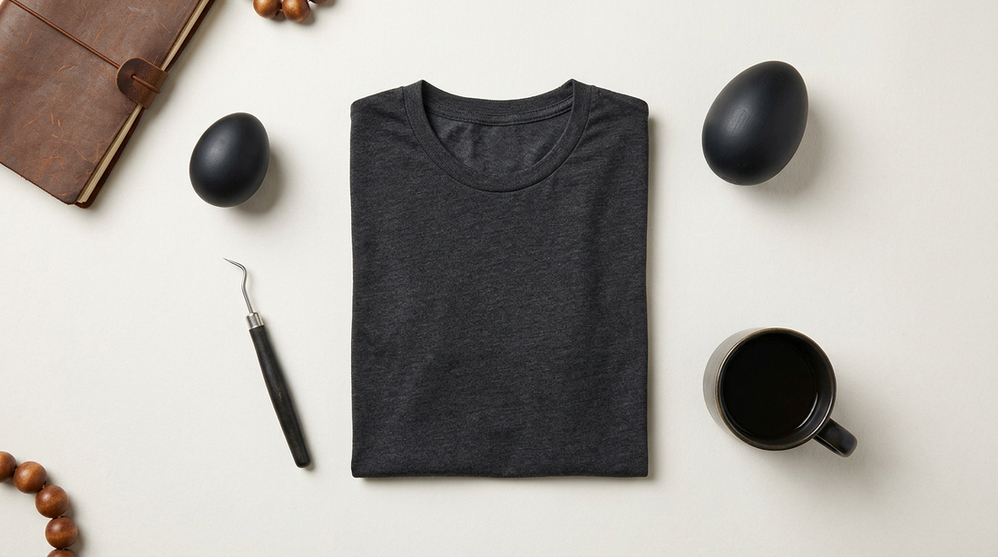 Flat lay of a dark heather grey t-shirt blank with crafting tools and edgy Easter decor on a neutral workspace.
