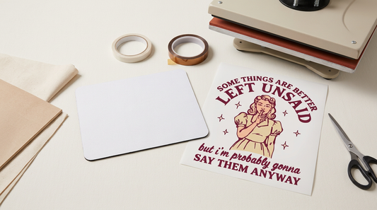 A clean crafting workspace showing a blank white mouse pad, printed sublimation transfer, and heat press.