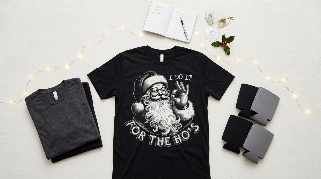 A festive workspace with blank t-shirts, can coolers, and holiday party props for creating adult humor Christmas apparel.