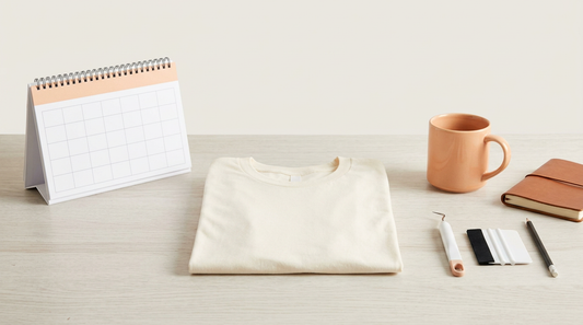 A clean workspace with a calendar, blank apparel, and crafting tools for planning seasonal print on demand projects.