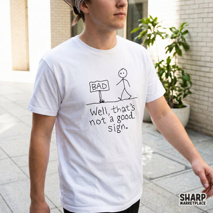 Sarcastic stick figure design featuring a person walking by a sign that says BAD with the quote Well, that is not a good sign on a white shirt.