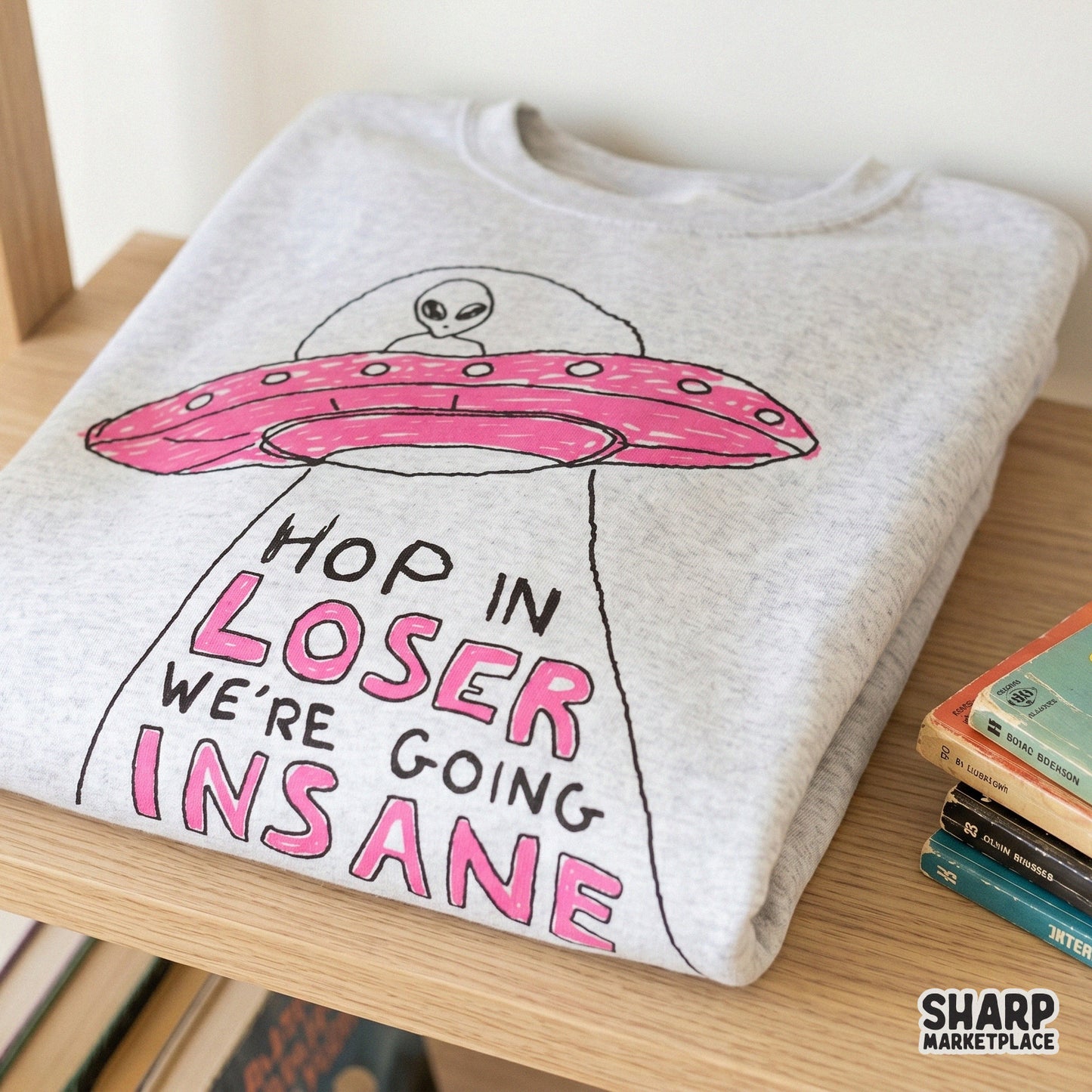 Trendy alien UFO graphic with playful typography and a pink spacecraft, perfect for custom t-shirt designs, stickers, or retro-themed apparel.