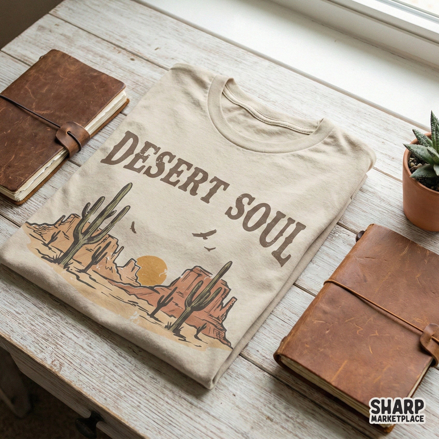 Vintage boho desert landscape graphic on a t-shirt mockup, showcasing saguaro cacti, mountain mesas, and a golden sun for custom apparel.
