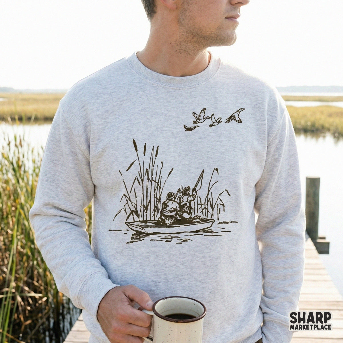 A rustic monochromatic duck hunting scene featuring hunters in a small boat, displayed as a digital design on a light gray crewneck sweatshirt.