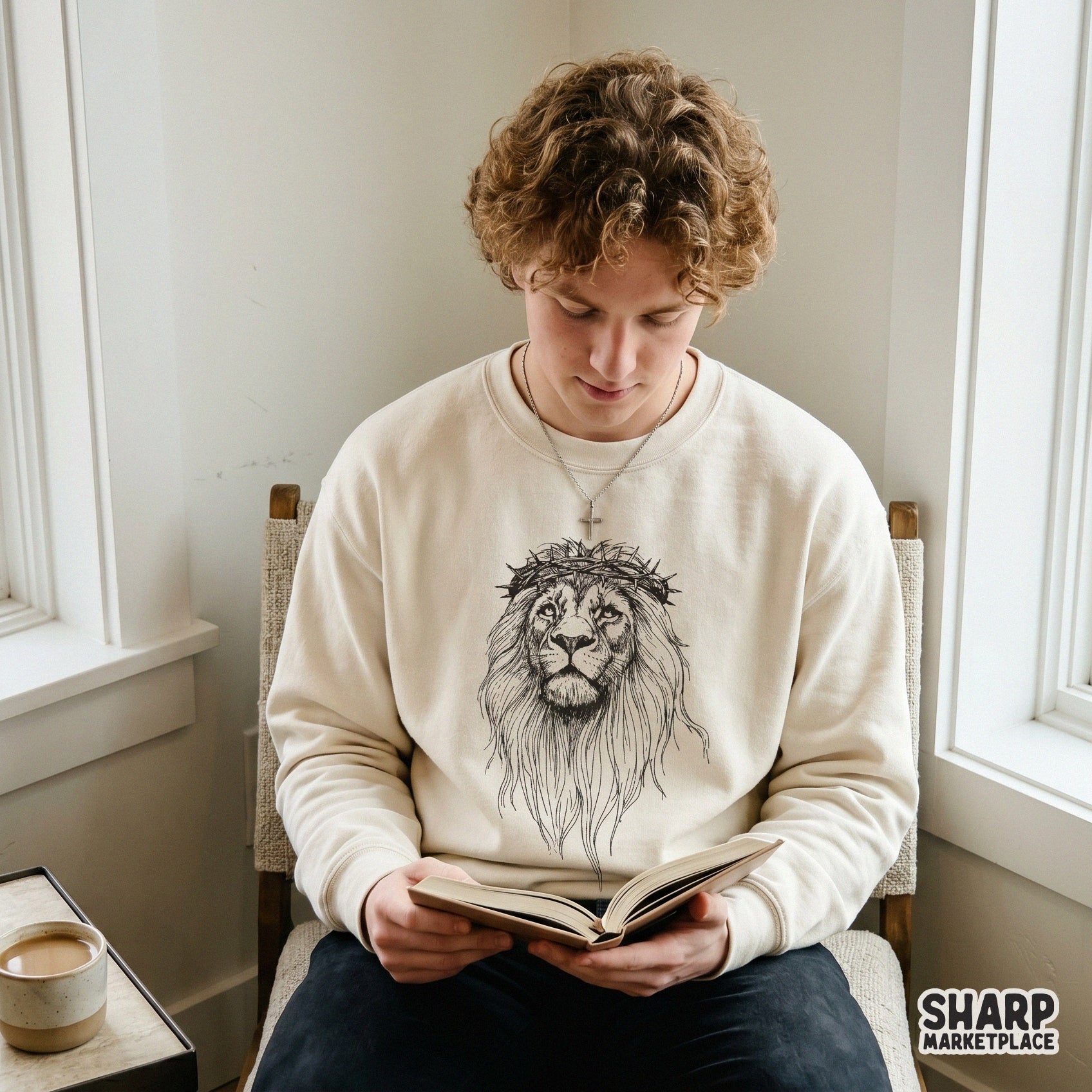 A monochromatic sketch of a lion with a crown of thorns printed on a cream-colored sweatshirt, ideal for faith-based clothing designs.