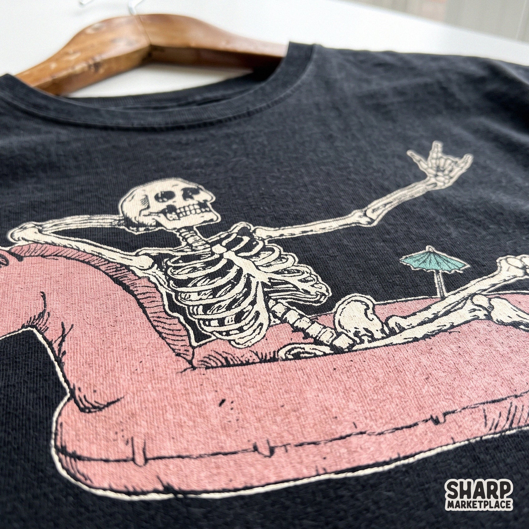 Relaxing skeleton lounging in a unicorn floatie, retro summer goth aesthetic for spooky season sublimation designs
