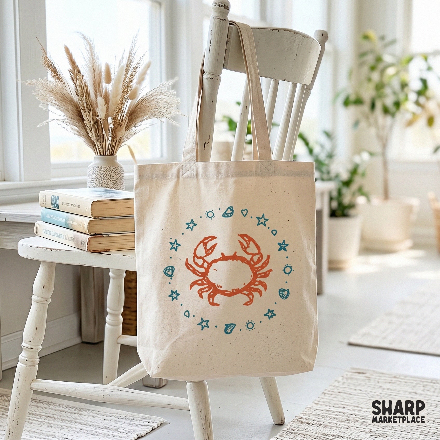 Digital design of a hand-drawn orange crab surrounded by a nautical ring of teal shells and starfish, displayed on a canvas tote bag mockup.