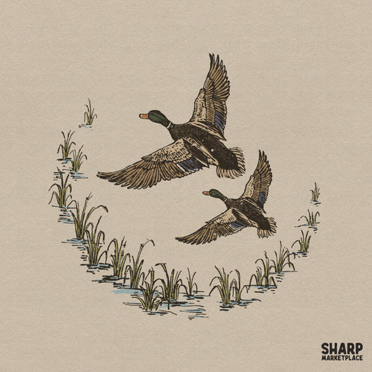 Two mallard ducks in flight over a crescent of marsh grass, detailed hand-drawn style for hunting apparel and outdoor sublimation projects.