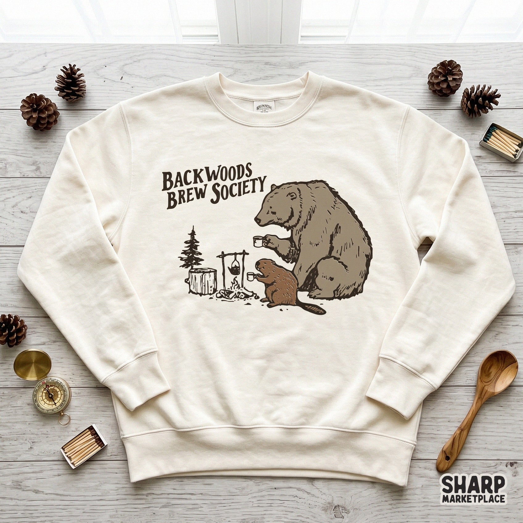 Digital sublimation design of a bear and beaver camping scene with coffee mugs and a campfire, perfect for rustic apparel or outdoor gear.
