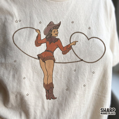 Vintage pinup cowgirl throwing a heart rope lasso in a retro western style Valentine's Day sublimation design