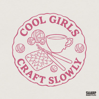 Dusty rose circular design featuring a coffee cup, yarn skeins, a crochet hook, and a granny square with the text Cool Girls Craft Slowly.