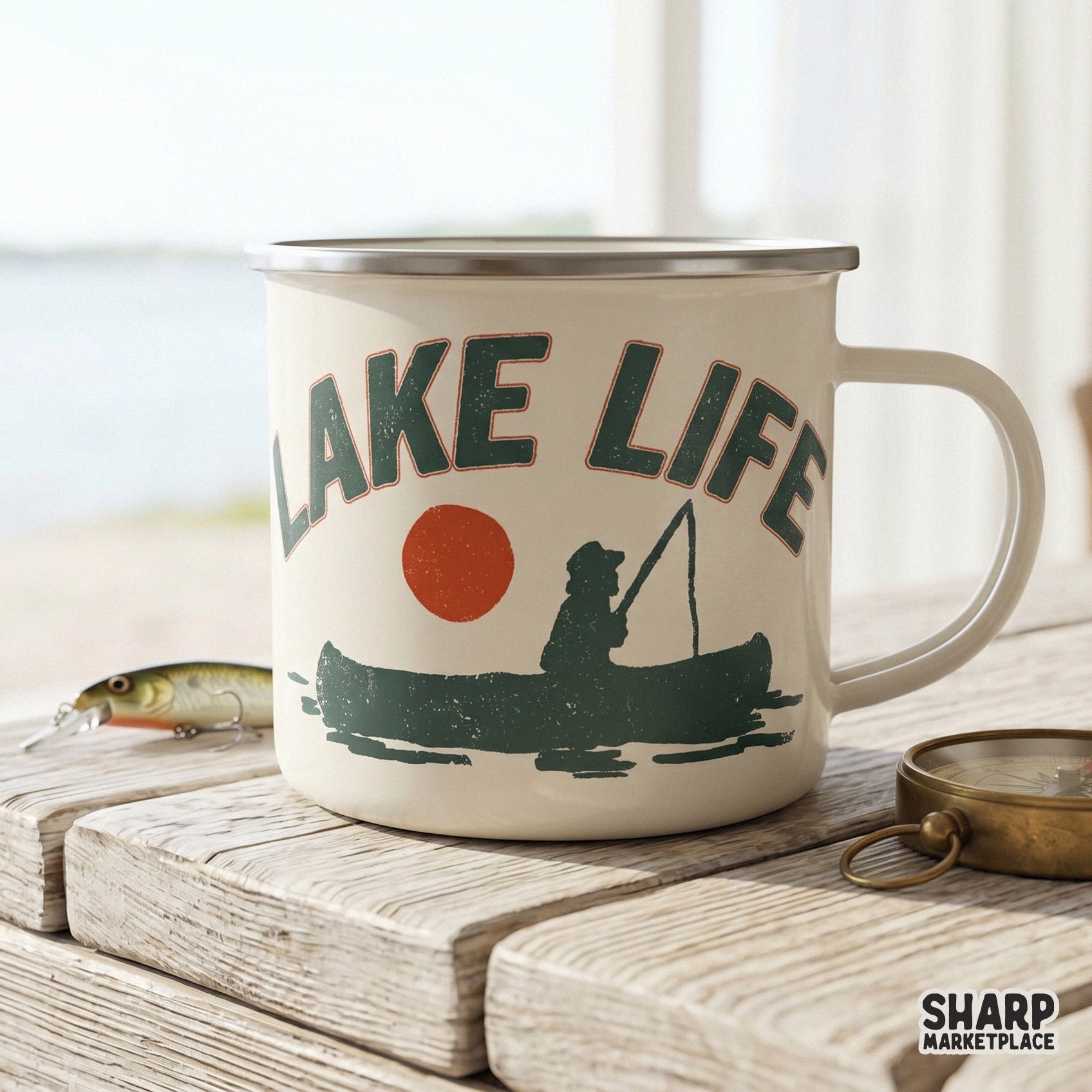 Vintage style Lake Life graphic on an enamel mug, showing a silhouette of a person fishing in a canoe with a bold red sun and arched text.
