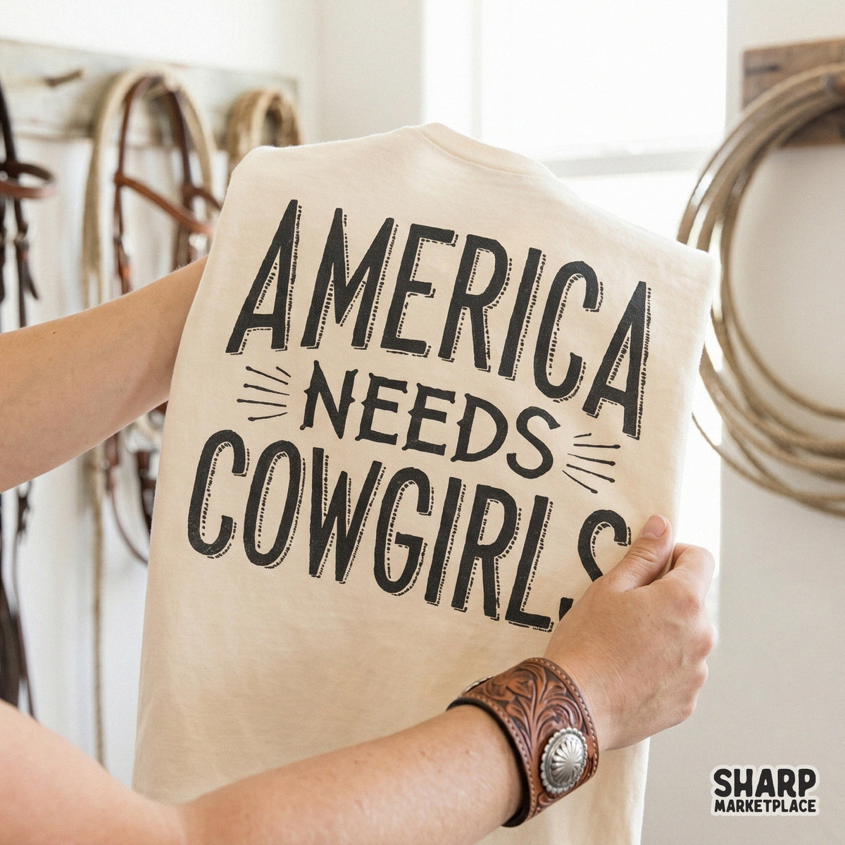 Rustic western graphic featuring the quote America Needs Cowgirls in block letters with speed lines, perfect for custom rodeo t-shirts and sublimation.