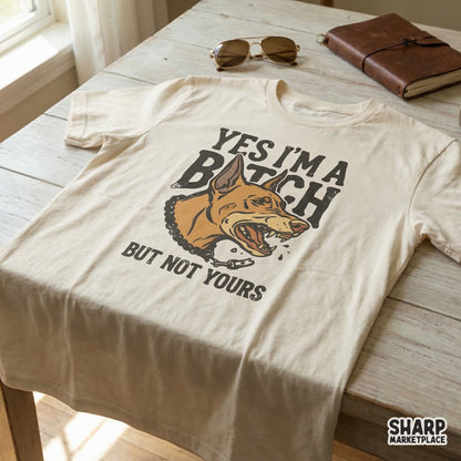 A cream-colored t-shirt featuring a snarky Doberman design with the text Yes I'm A Bitch But Not Yours, perfect for custom DIY clothing projects.