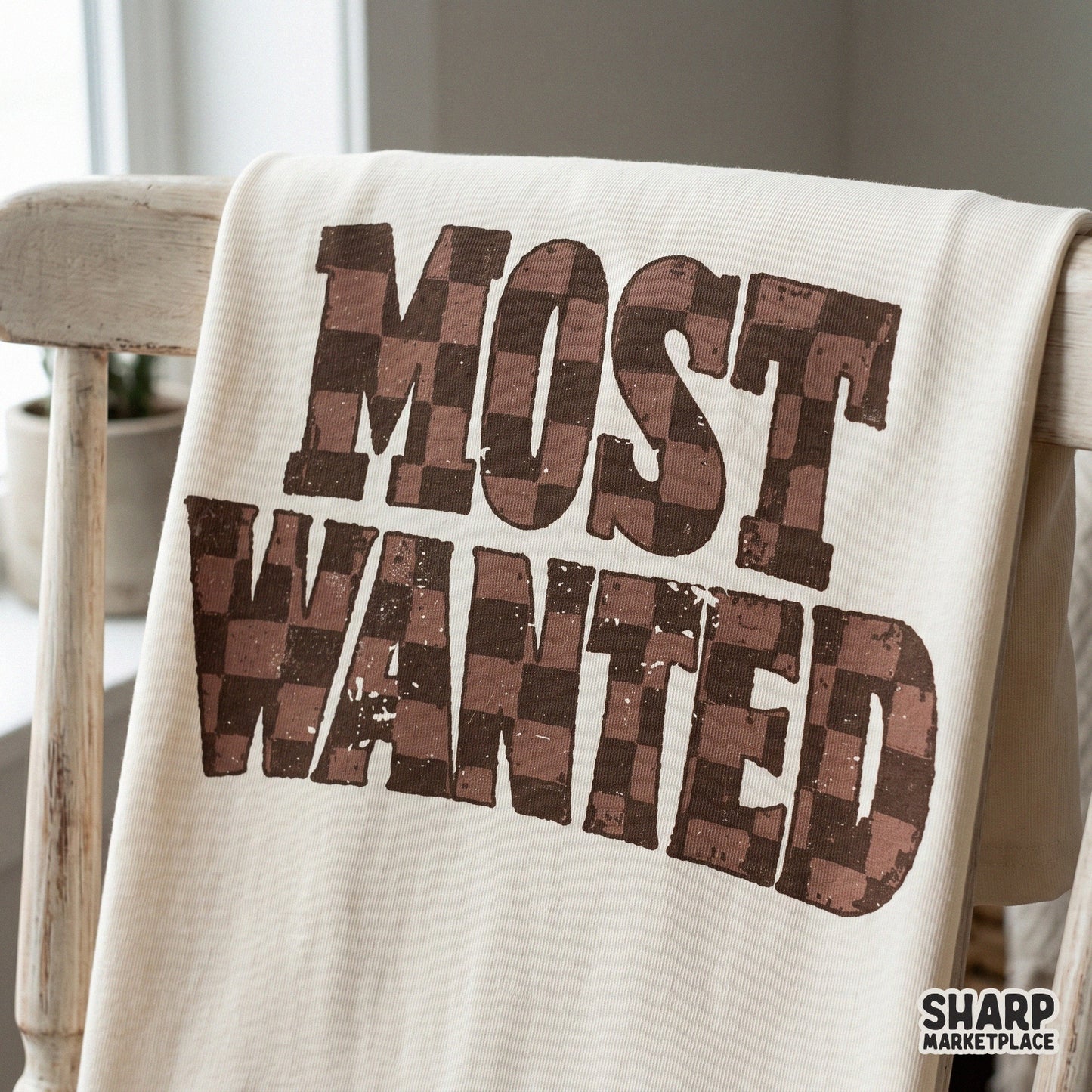 Bold Most Wanted text design with a worn, outlaw-inspired look and earth-toned checkered pattern for trendy western print-on-demand items.