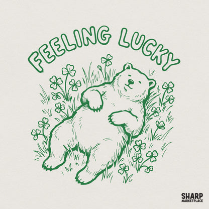 Retro green line art design featuring a relaxed bear lounging in a field of clovers with the text Feeling Lucky arched above for St. Patrick's Day.