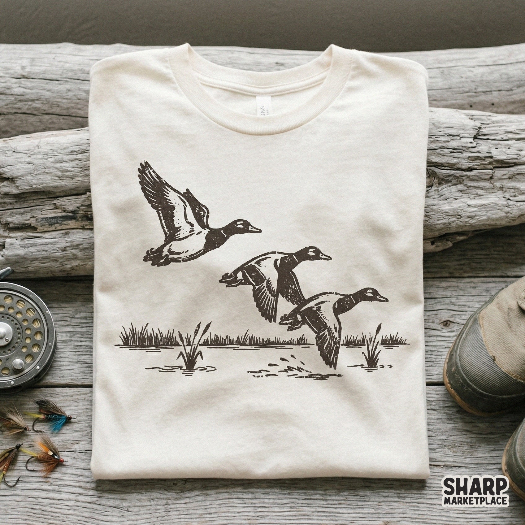 Rustic black and white duck trio design printed on a neutral-colored t-shirt, featuring a detailed hand-drawn style for outdoor-themed apparel.
