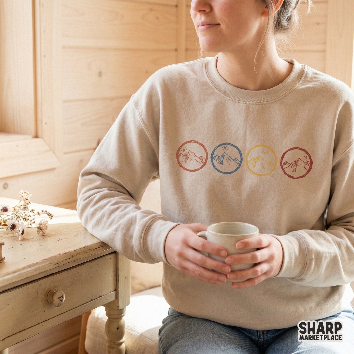 A beige sweatshirt featuring four retro mountain circle designs in a horizontal row, perfect for custom apparel, camping gear, and outdoor sublimation.