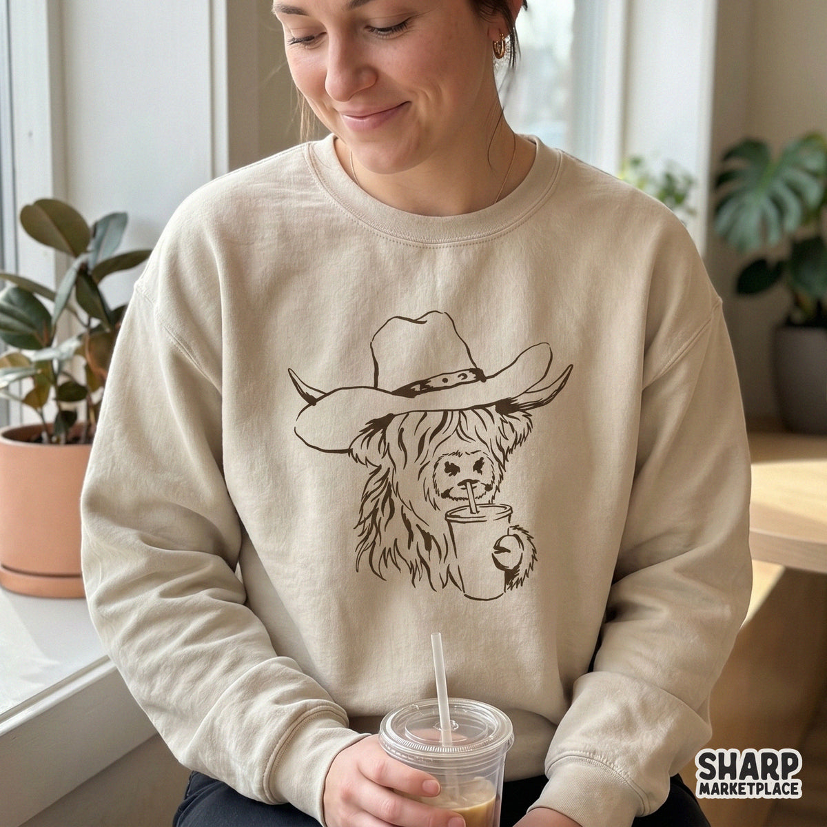 Rustic ranch-style graphic of a Highland cow sipping a beverage, ideal for creating trendy western apparel and DIY tumblers.