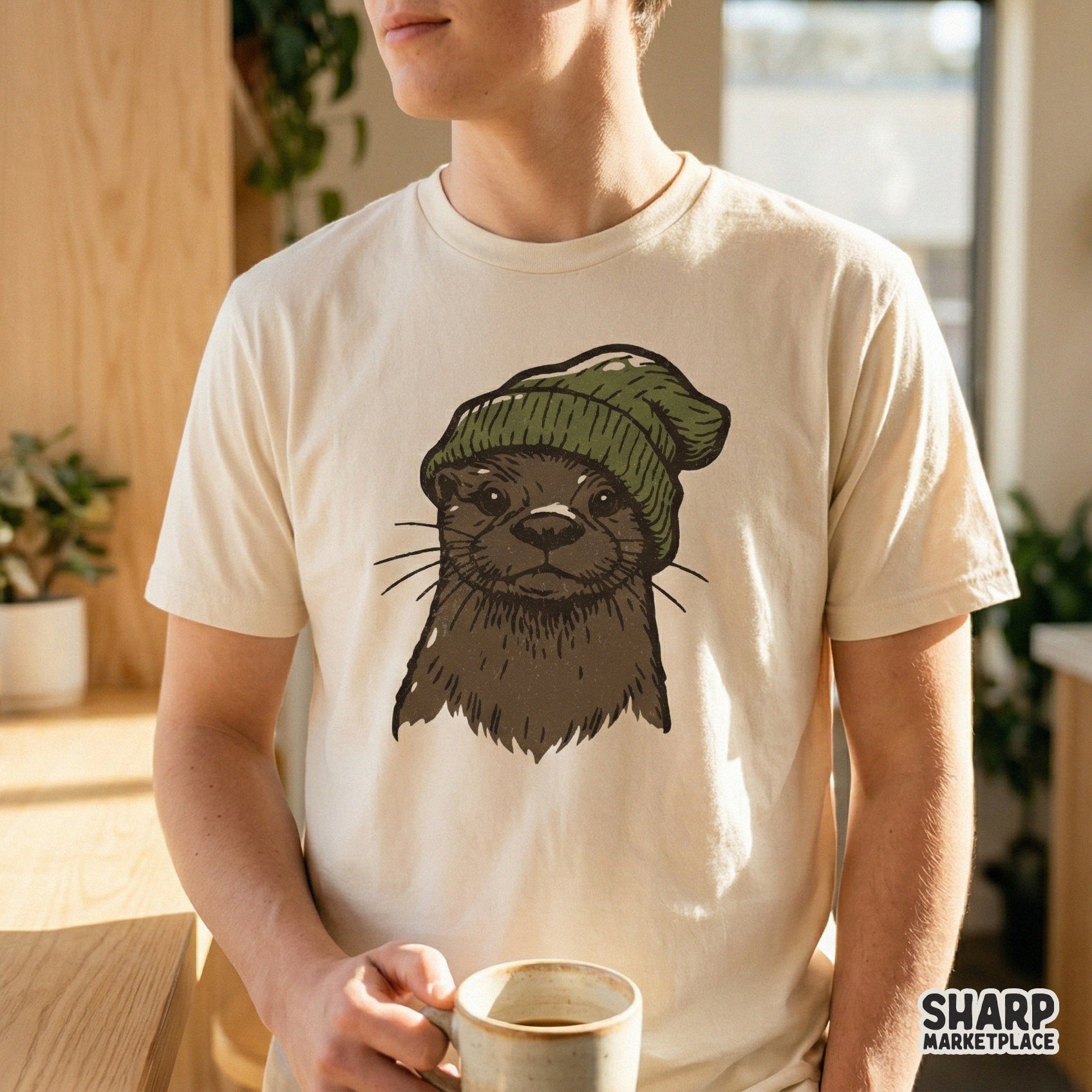 Digital design of an adorable otter in a cozy green winter hat, showcased on a light-colored t-shirt for a trendy woodland-inspired look.