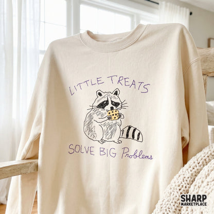 Whimsical raccoon illustration with a cookie and the quote Little Treats Solve Big Problems, a funny mental health humor design for printable crafts.