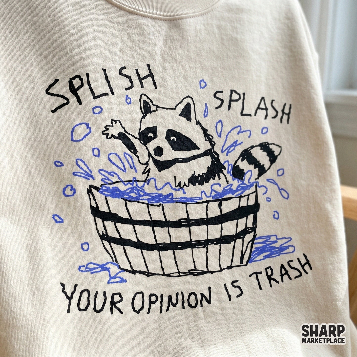 Digital sublimation design featuring a sketchy black and white raccoon in a tub with blue water accents and the funny phrase Splish Splash Your Opinion Is