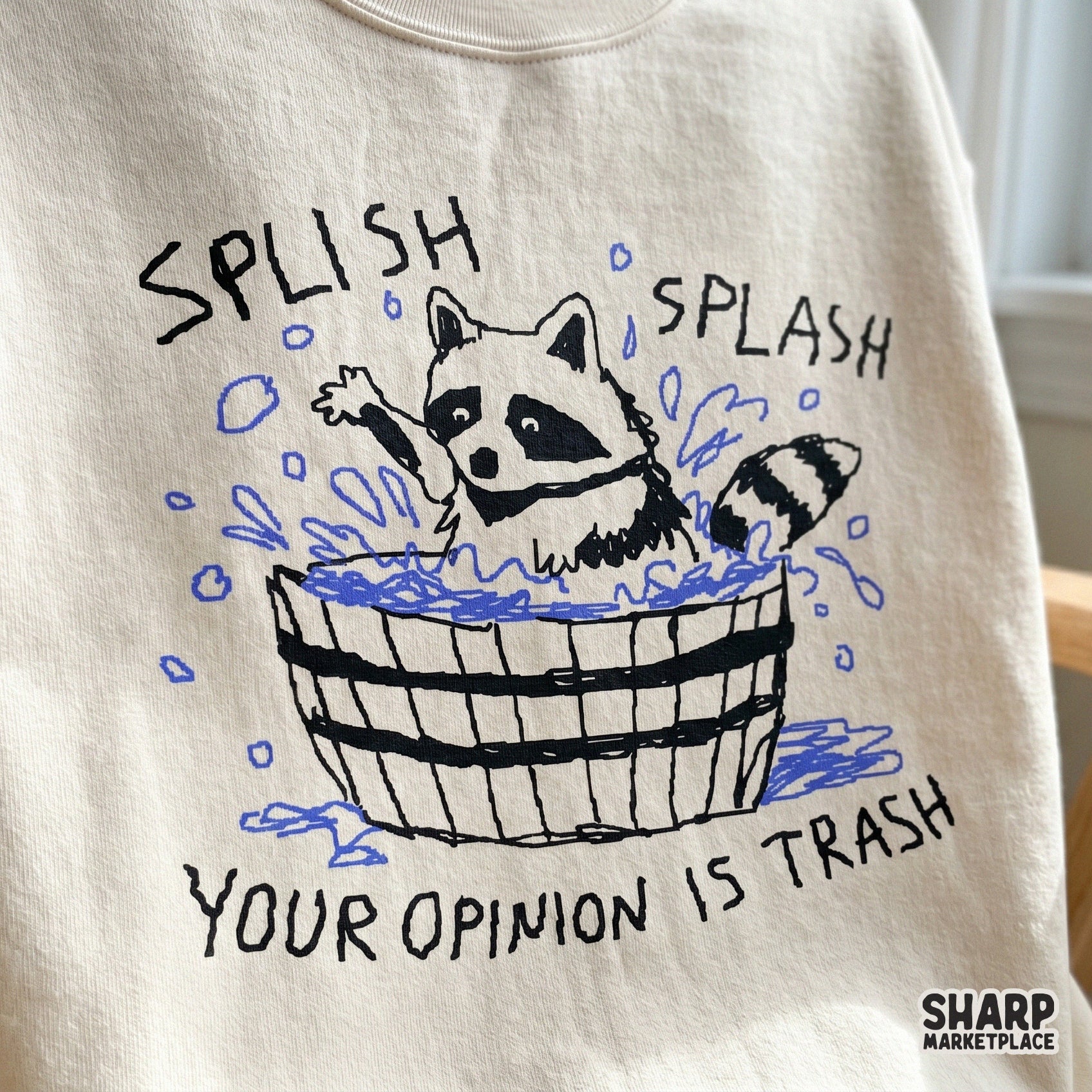 Digital sublimation design featuring a sketchy black and white raccoon in a tub with blue water accents and the funny phrase Splish Splash Your Opinion Is