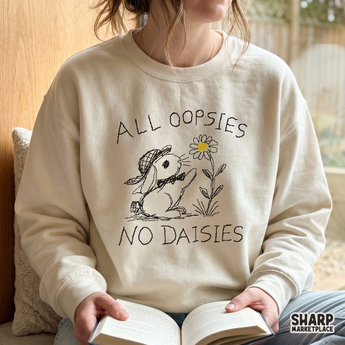 Beige sweatshirt featuring a hand-drawn rabbit reaching for a flower with the witty quote All Oopsies No Daisies in a charming sketch aesthetic.
