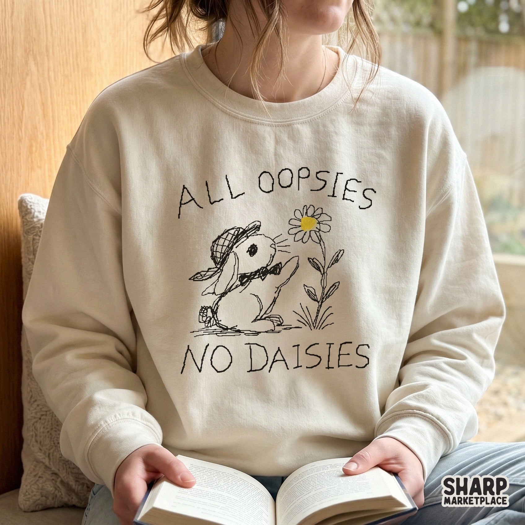 Beige sweatshirt featuring a hand-drawn rabbit reaching for a flower with the witty quote All Oopsies No Daisies in a charming sketch aesthetic.