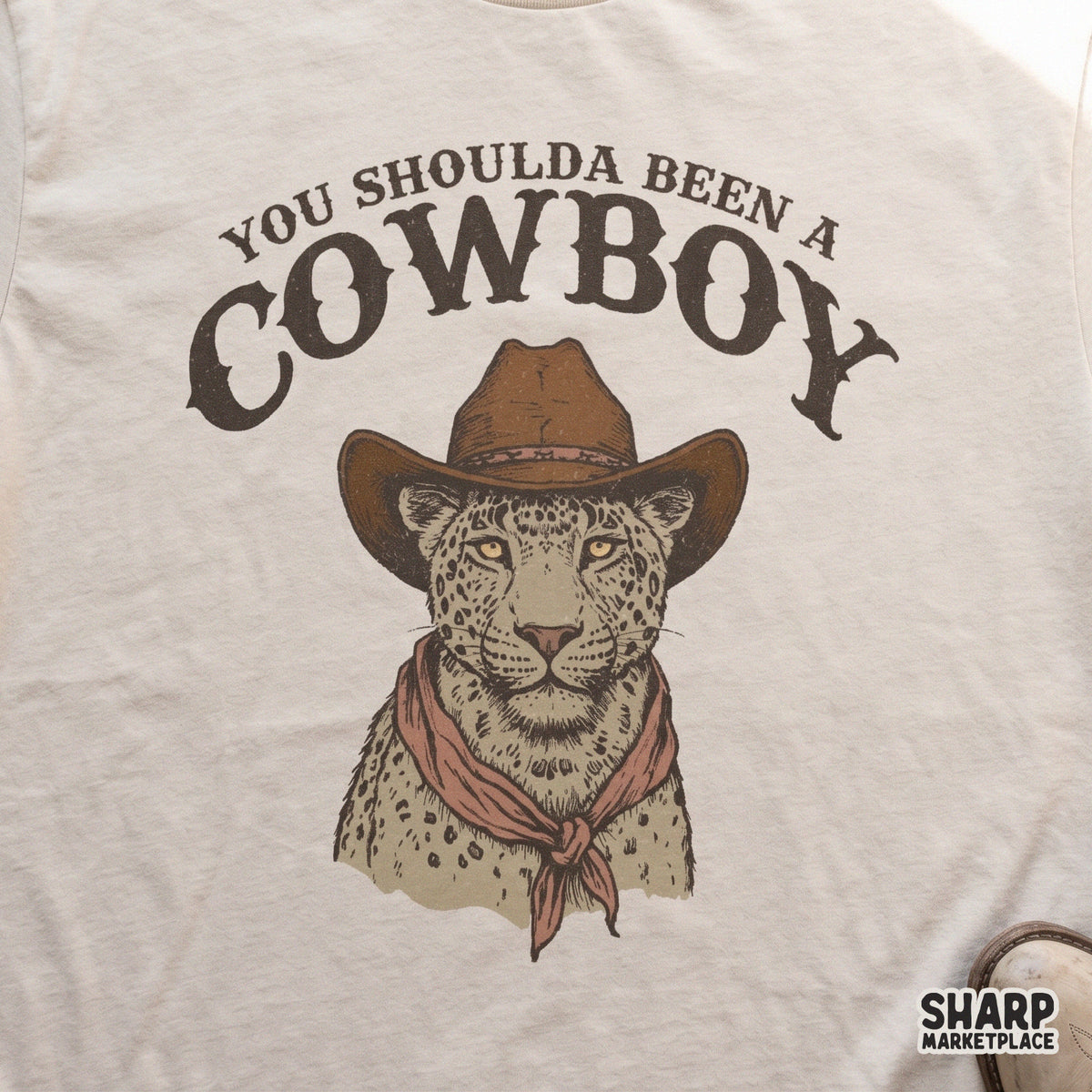 Spotted feline wearing a classic cowboy hat and bandana with distressed western text, a versatile digital download for print-on-demand projects.