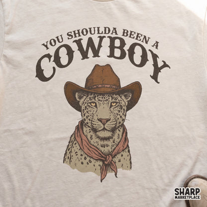 Spotted feline wearing a classic cowboy hat and bandana with distressed western text, a versatile digital download for print-on-demand projects.