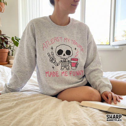 Digital design featuring a cute skeleton with a coffee cup and the sarcastic quote At Least My Trauma Made Me Funny for apparel sublimation.