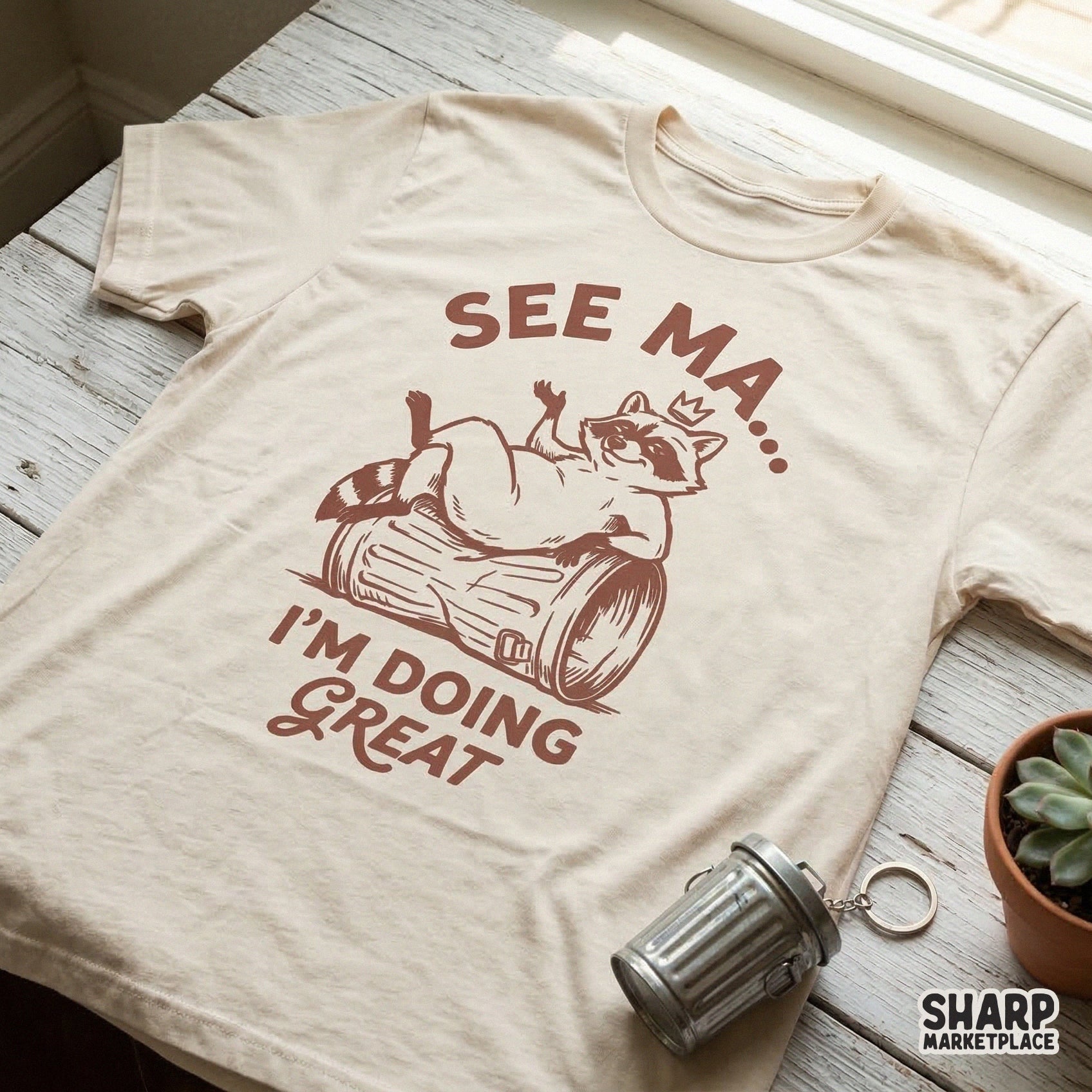 Digital download design featuring a cheeky raccoon sitting on a trash can with a crown and the retro text See Ma I'm Doing Great for sublimation.