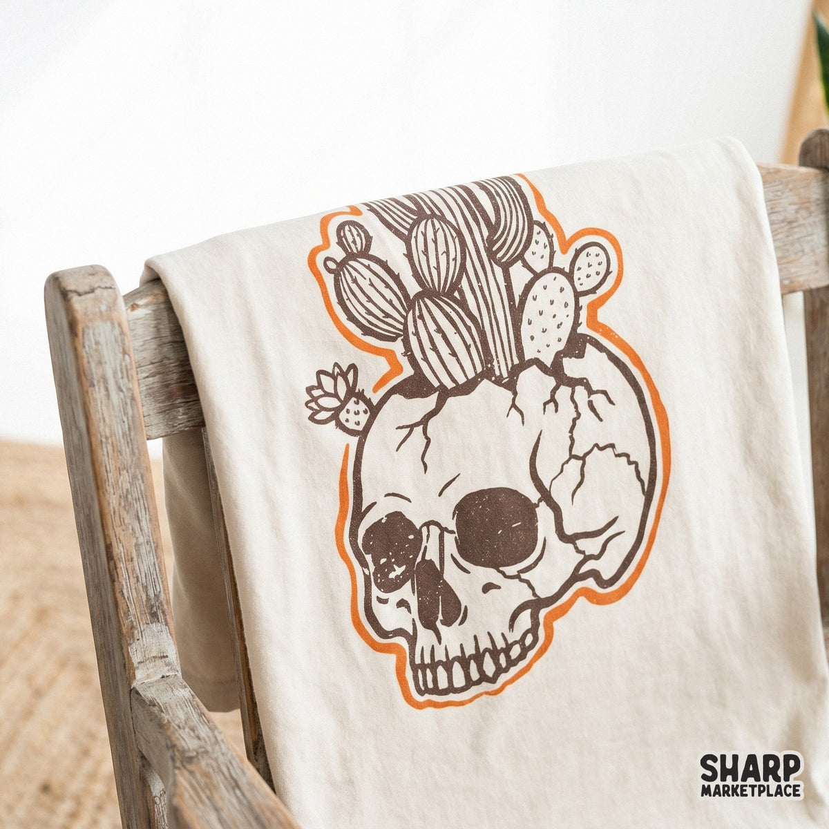Boho desert skull graphic with saguaro and prickly pear cacti, rendered in a rustic sticker style with a vibrant orange border for sublimation.