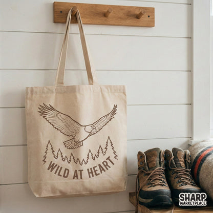 Vintage-inspired eagle soaring over pine trees with Wild At Heart lettering, ideal for creating custom wilderness stickers, tumblers, and outdoor gear.