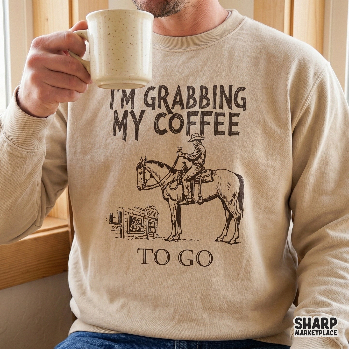 Beige sweatshirt featuring a hand-drawn cowboy design with the funny quote I'm Grabbing My Coffee To Go, perfect for rustic apparel and DIY projects.