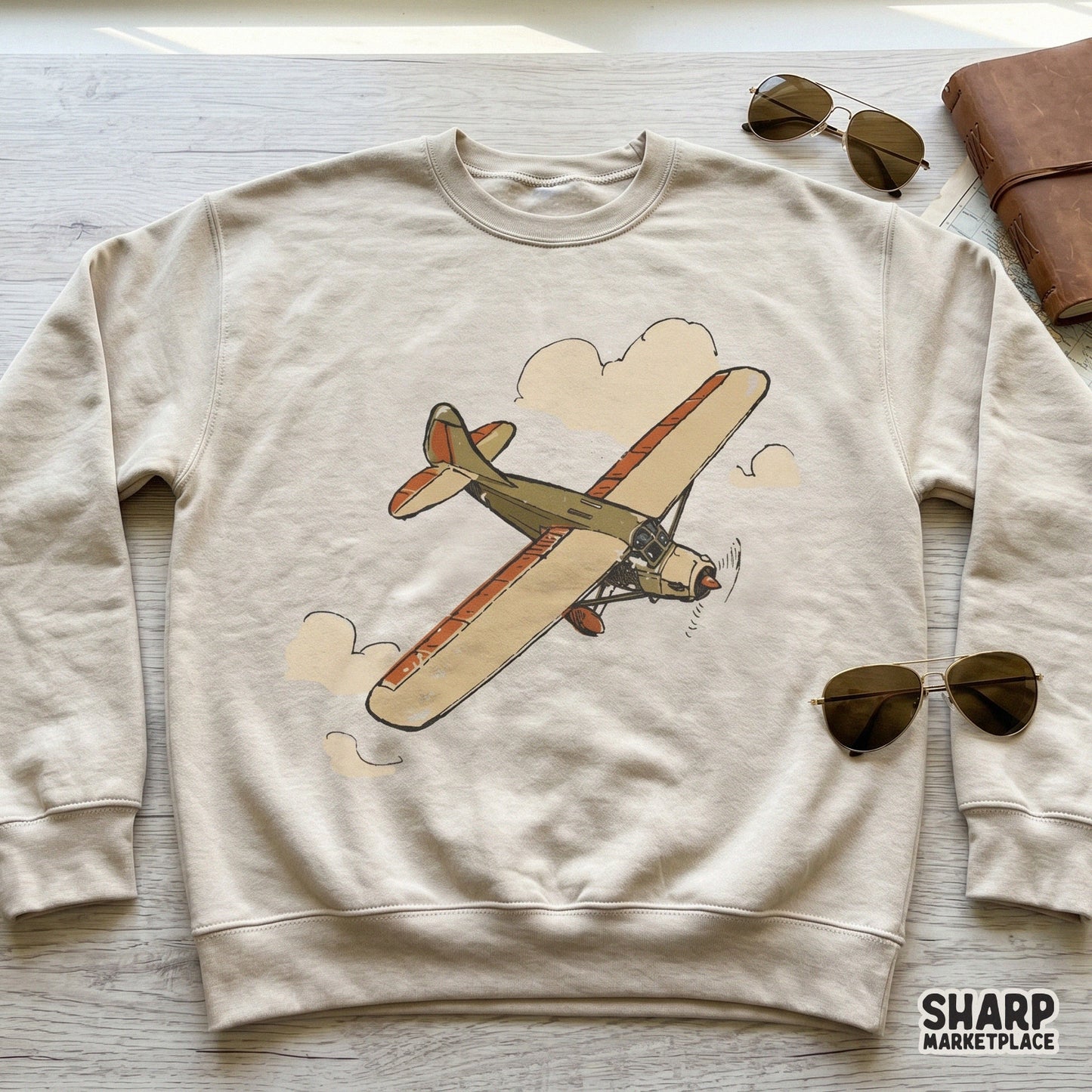 Retro style monoplane soaring through clouds, featured as a digital design on a beige sweatshirt for streetwear or travel-themed clothing projects.