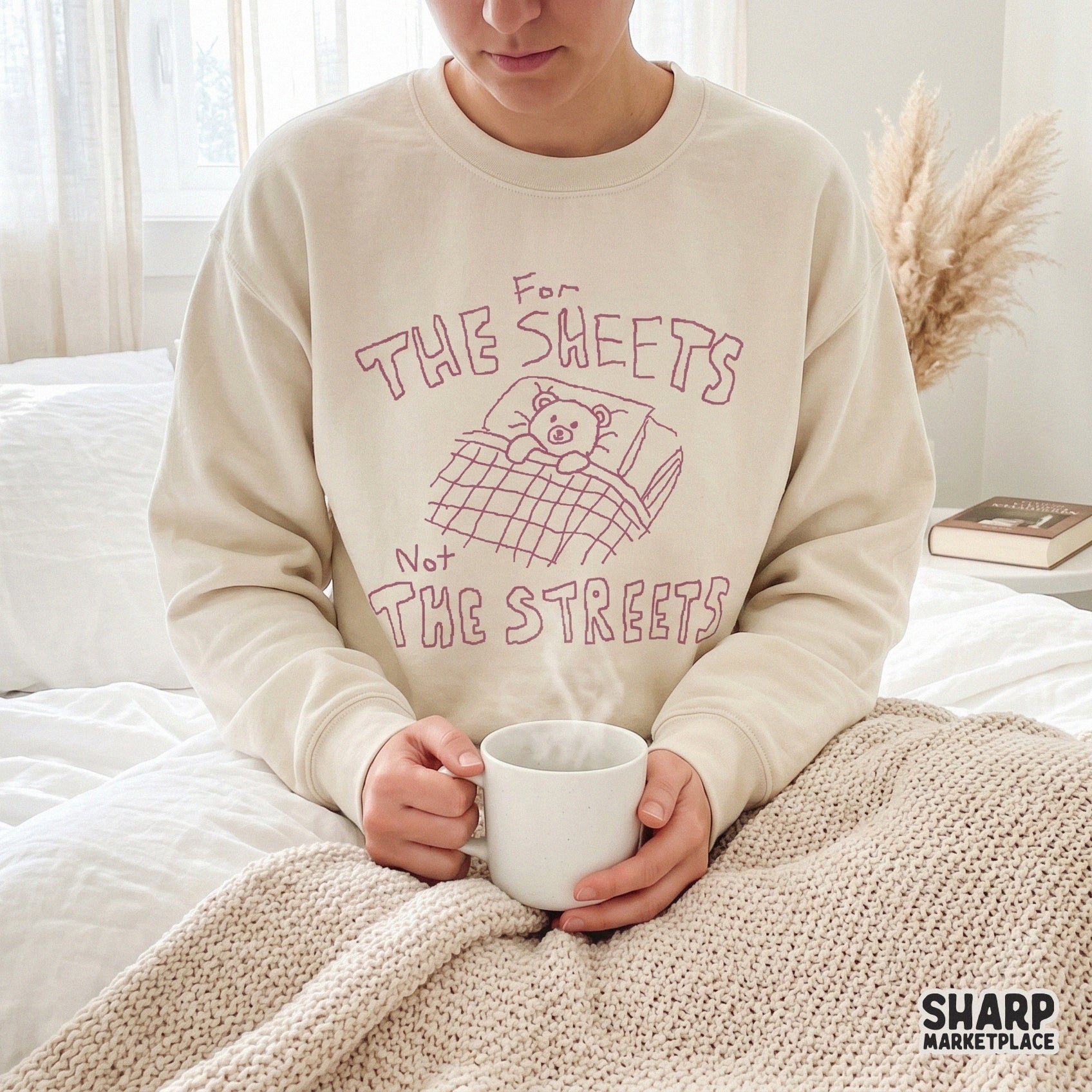 Cozy aesthetic apparel mockup displaying a pink hand-drawn teddy bear illustration and the witty quote For The Sheets Not The Streets.