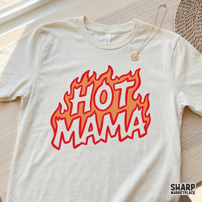 Retro style Hot Mama text graphic featuring a fiery flame motif displayed on a cream colored t-shirt mockup.