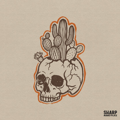 Vintage brown ink skull planter with various desert cacti and a blooming succulent, featuring a bold orange die-cut outline for western apparel.