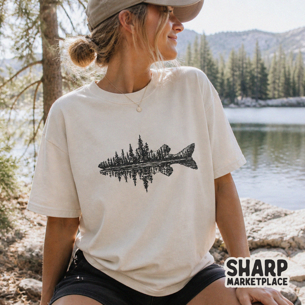 T-shirt mockup featuring a black ink fish silhouette design with a double exposure forest and lake reflection, perfect for nature-themed clothing.