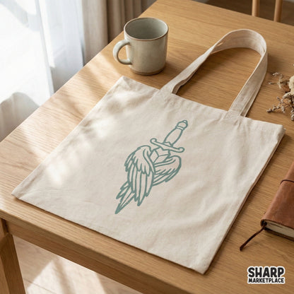 A canvas tote bag mockup featuring a centered teal angel sword with wings graphic, perfect for custom apparel and sublimation printing designs.