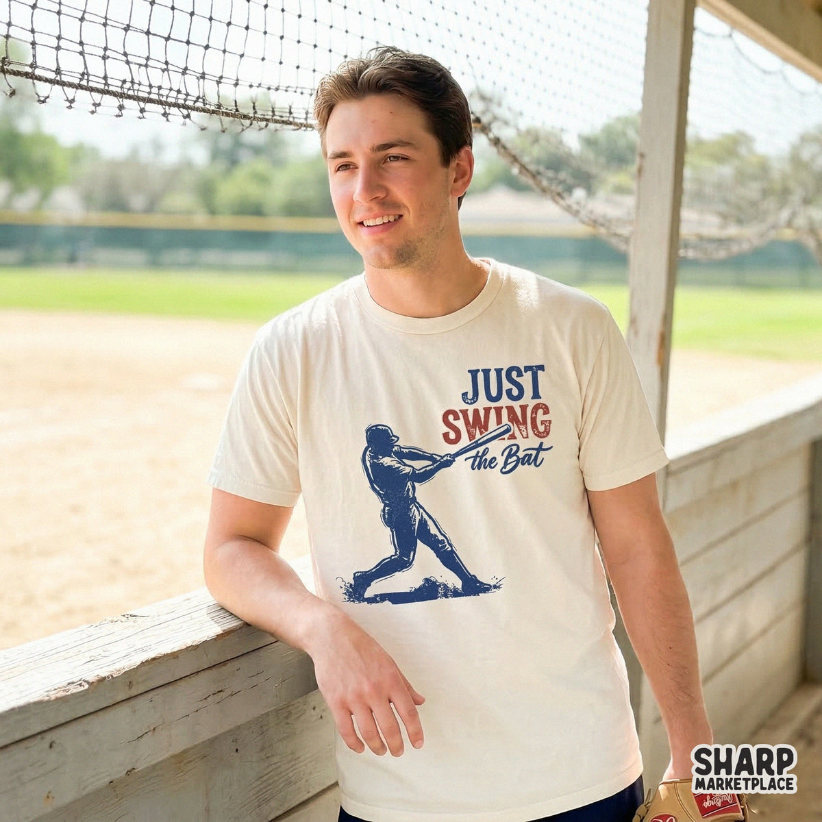 Cream-colored t-shirt featuring a vintage baseball graphic with a batter swinging and the inspirational quote Just Swing the Bat in red and navy.