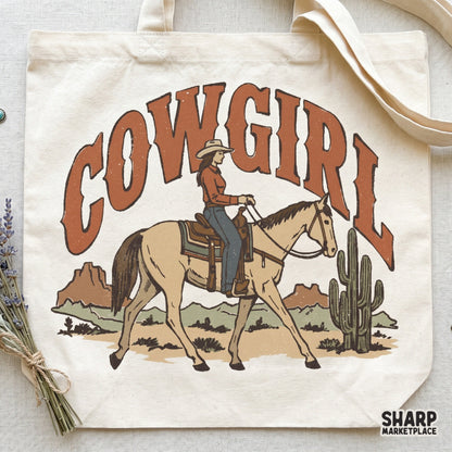 Digital western graphic for apparel featuring a cowgirl riding a horse, desert scenery, and rustic burnt-orange lettering for sublimation projects.