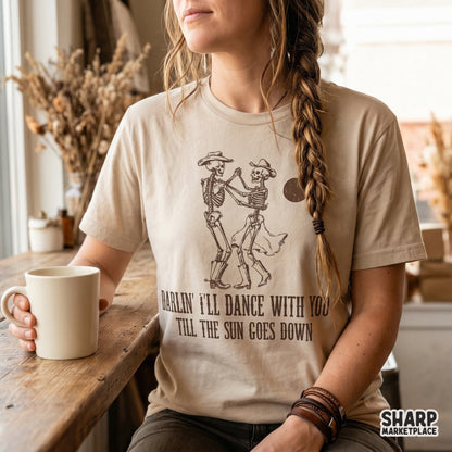 A retro western sublimation graphic on a t-shirt showing two skeletons dancing under a sun with the text Darlin I'll Dance With You Till The Sun Goes Down.