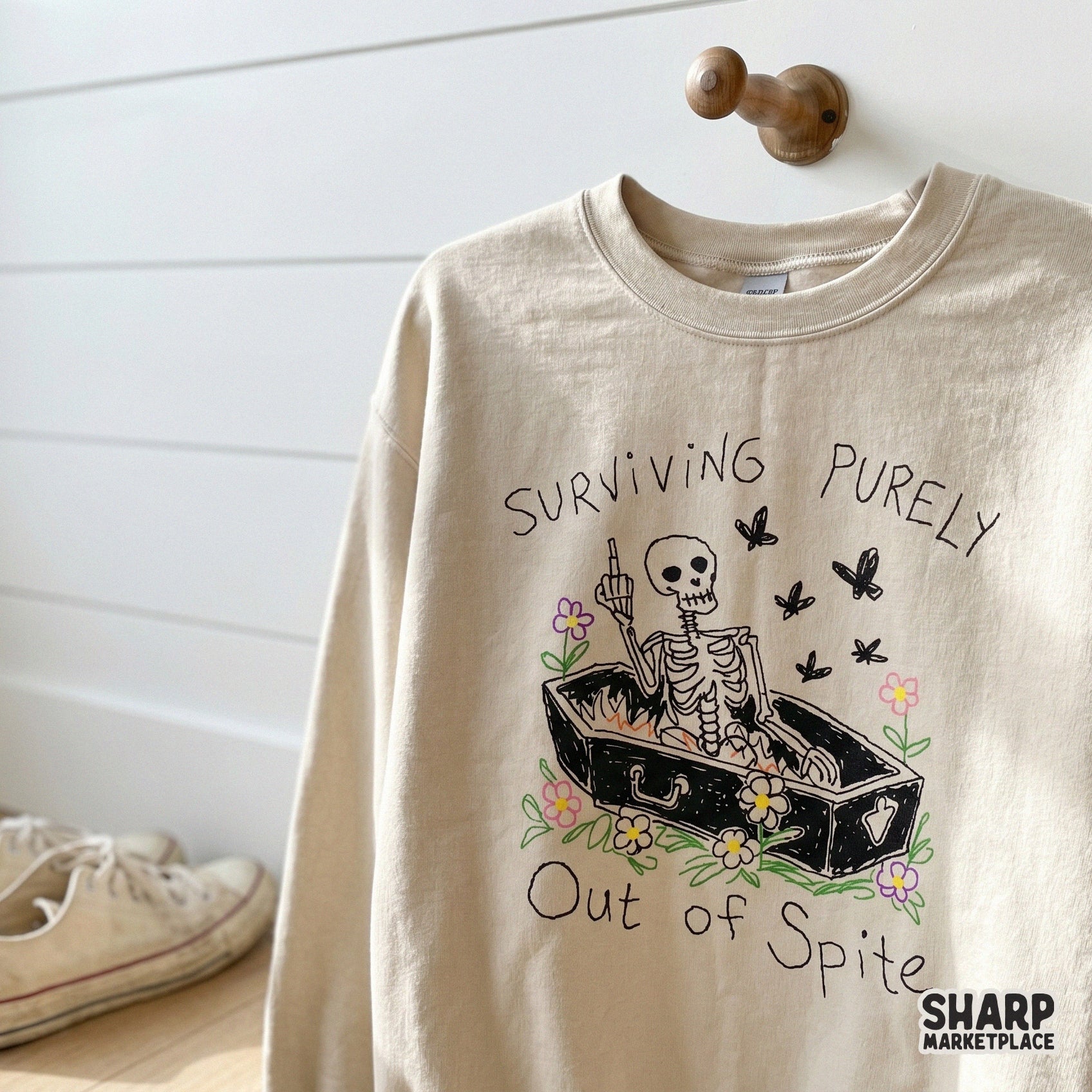 Funny gothic-style digital download for print-on-demand, featuring a skeleton in a coffin with the text Surviving Purely Out Of Spite and floral details.
