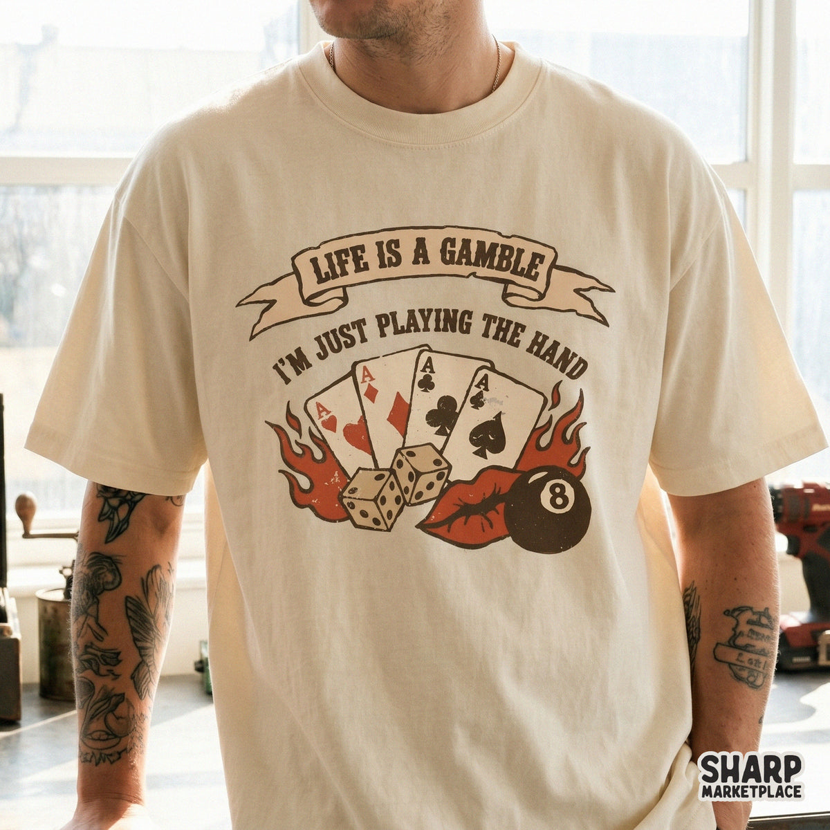 Vintage style sublimation graphic on a t-shirt showing a poker hand of four aces, dice, and an eight ball with the quote Life Is A Gamble I'm Just Playing The