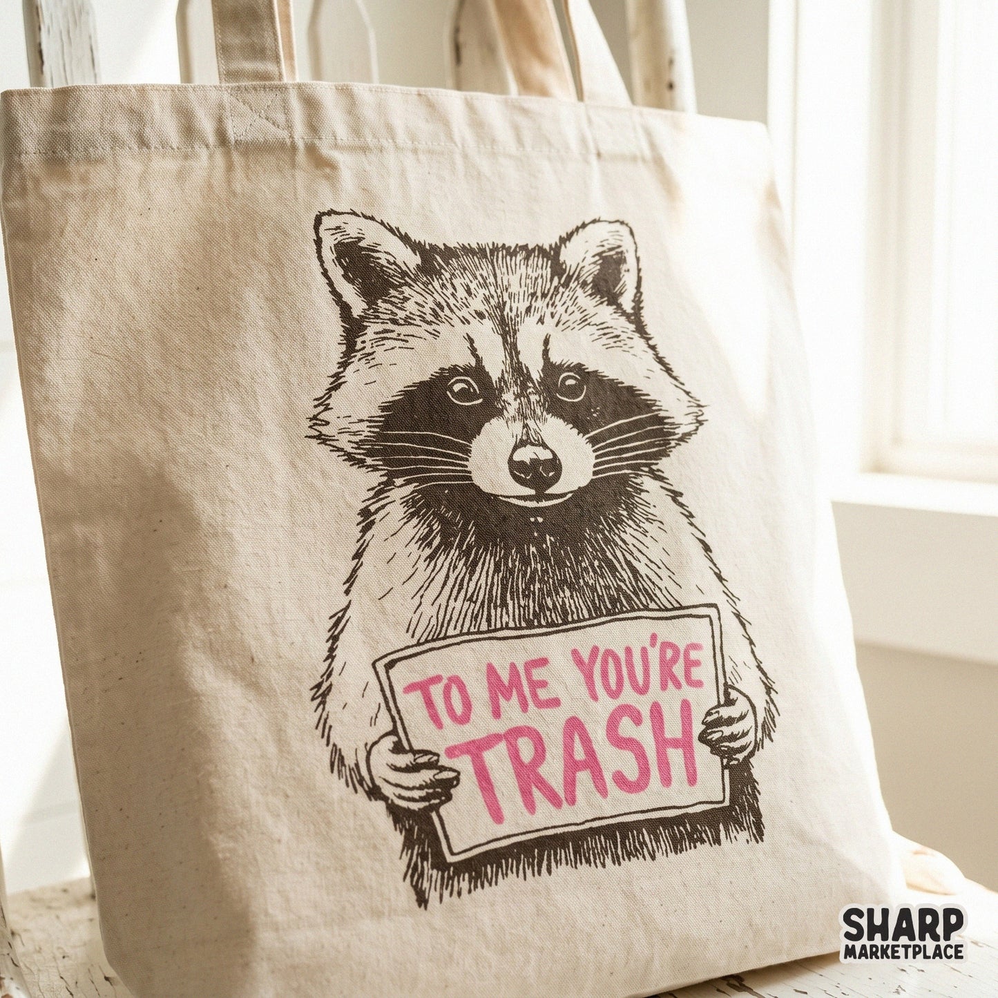 Detailed trash panda graphic with a sarcastic sign reading To Me You Are Trash displayed on a neutral-colored fabric tote bag mockup for apparel design.